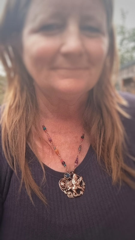 Woman wearing a necklace with a decorative pendant outdoors