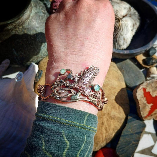 Close-up of a wrist wearing a decorative bracelet with natural elements on a rocky background.