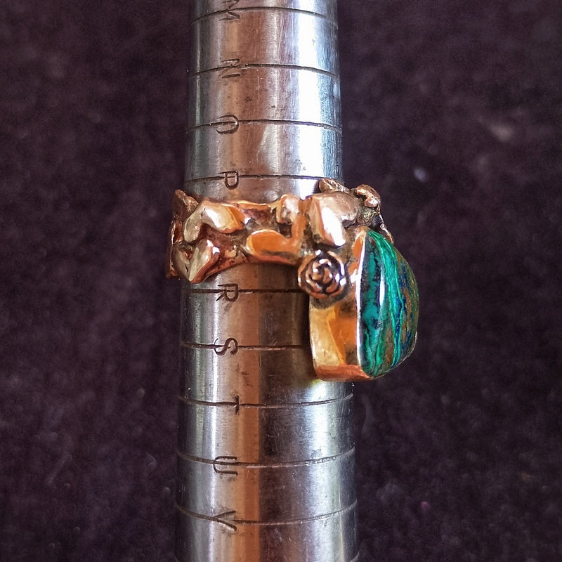Gold ring with green stone on a metal ruler