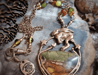 Necklace with hare rabbit pendant and jasper stone cabochon embedded stone on textured surface by artist and jewellery metalsmith Elizabeth Shewan