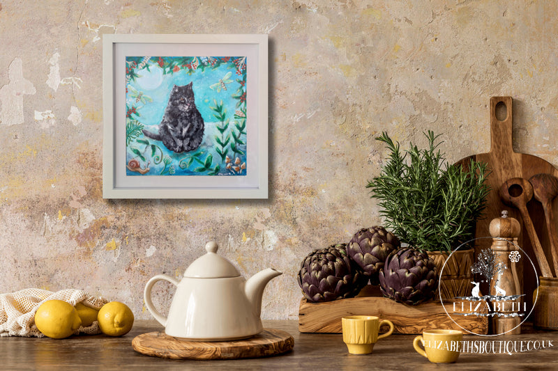 Framed artwork of a cat in an underwater scene above a kitchen counter with a teapot and lemons.