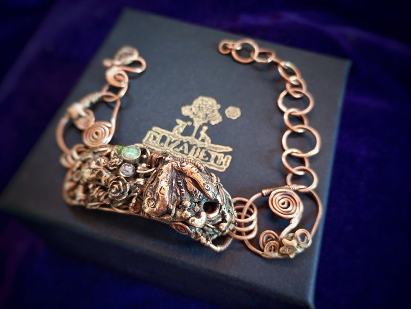 Bronze bracelet with intricate design on a black box with brand logo