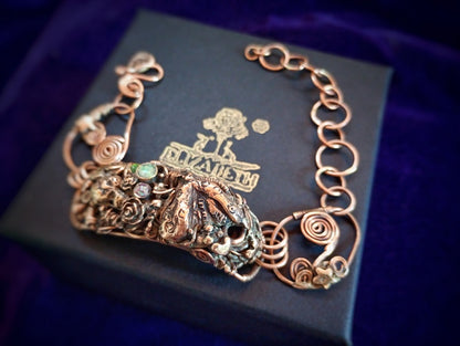 Bronze bracelet with intricate design on a black box with brand logo