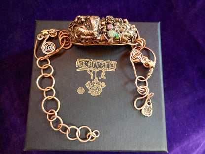 Bronze bracelet on a black box with 'Elizabeth' branding against a purple background