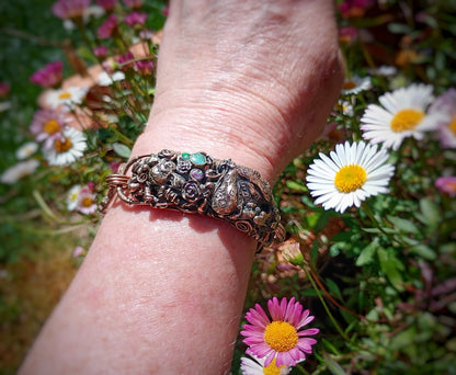 Decorative bracelet on a wrist with flowers in the background
