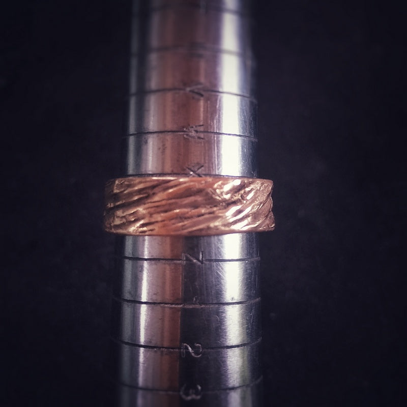 Close-up of a bronze tree imprint eternity ring on a ring sizer, size Y
