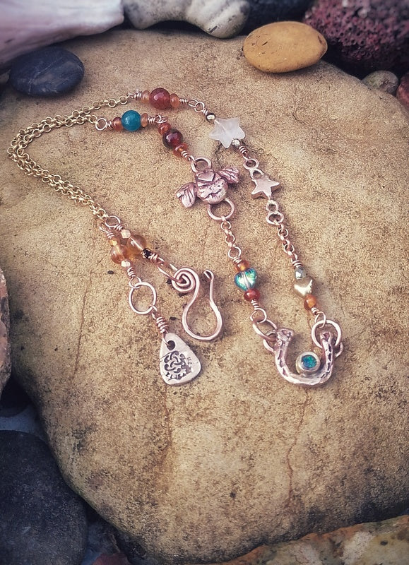 Good luck horse show lady luck Necklace with various charms and a lovebee on a stone surface