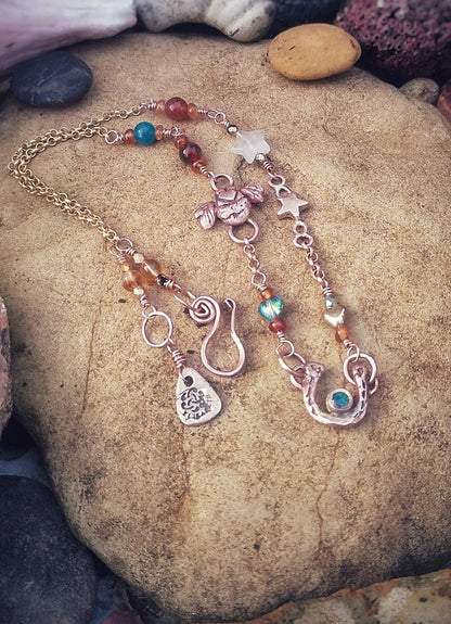 Good luck horse show lady luck Necklace with various charms and a lovebee on a stone surface