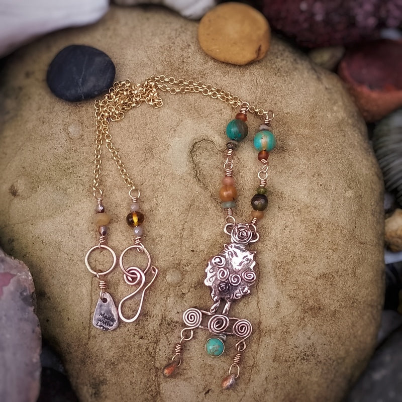 Jewelry handmade sheep necklace with beads and charms on a stone surface