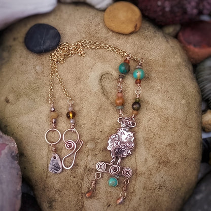 Jewelry handmade sheep necklace with beads and charms on a stone surface