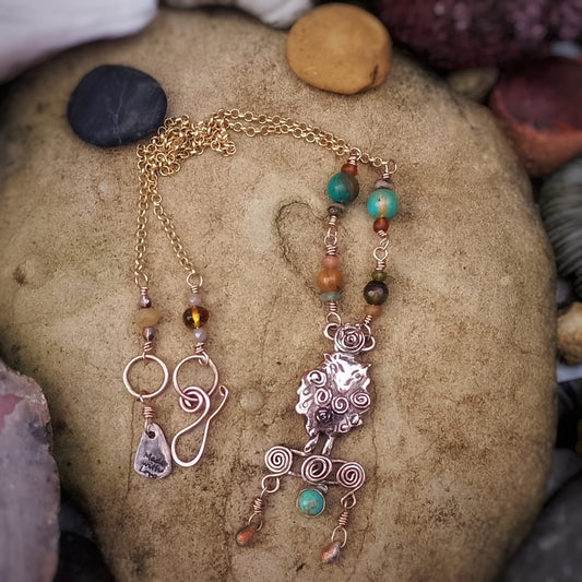 Jewelry handmade sheep necklace with beads and charms on a stone surface