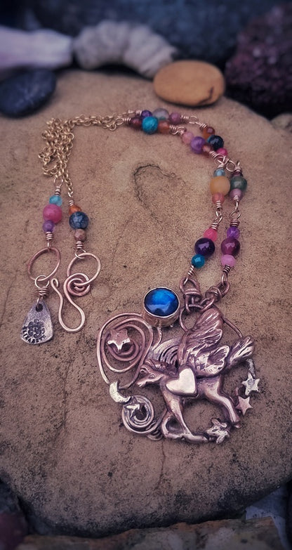 Necklace with a unicorn pendant and colorful beads on a stone surface