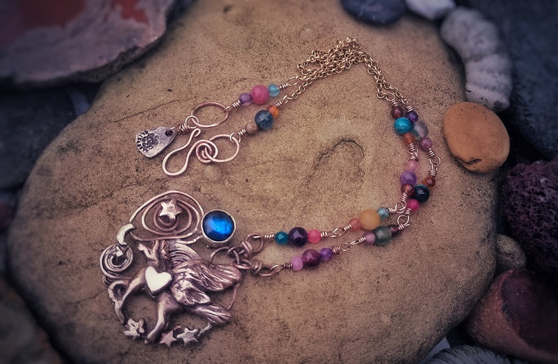 Necklace with fairy pendant and colorful beads on a stone surface