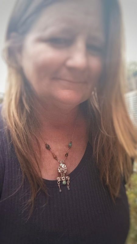 Woman wearing a bronze sheep necklace with a blurred background