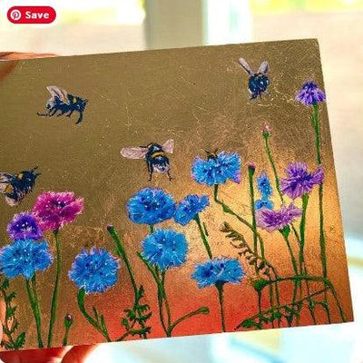 Painting with floral design and bee illustrations on a gold background, with a customer review below by Elizabeth Shewan