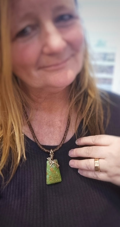 Woman wearing a necklace with a green pendant indoors