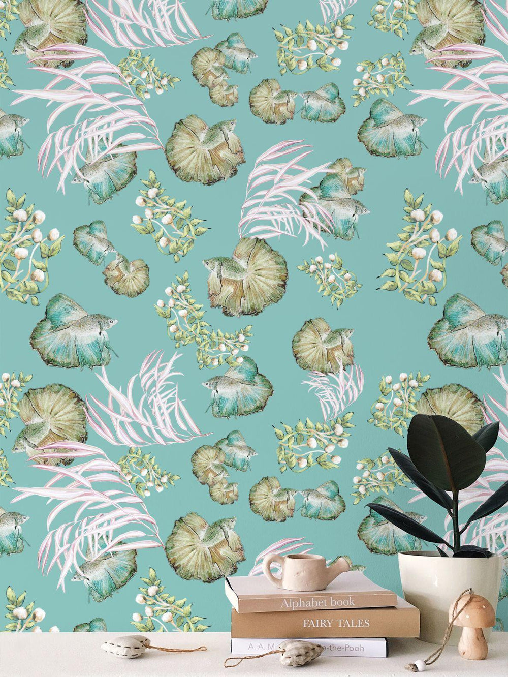 Seashell and seaweed pattern with fish on a teal background with books and a plant in the foreground.