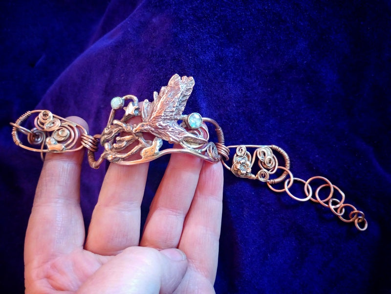 Decorative brooch held by a hand against a dark background