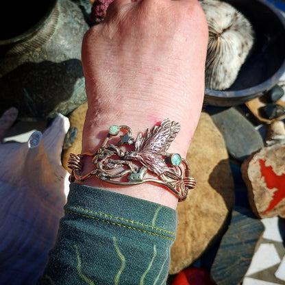 Close-up of a wrist wearing a decorative bracelet with natural elements on a rocky background.