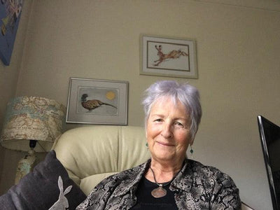 Woman sitting on a couch in a room with framed pictures on the wall.